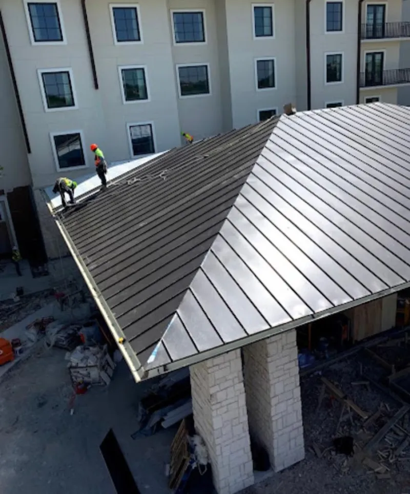 Crew installing standing seam metal roof panels on a commercial project in Butler